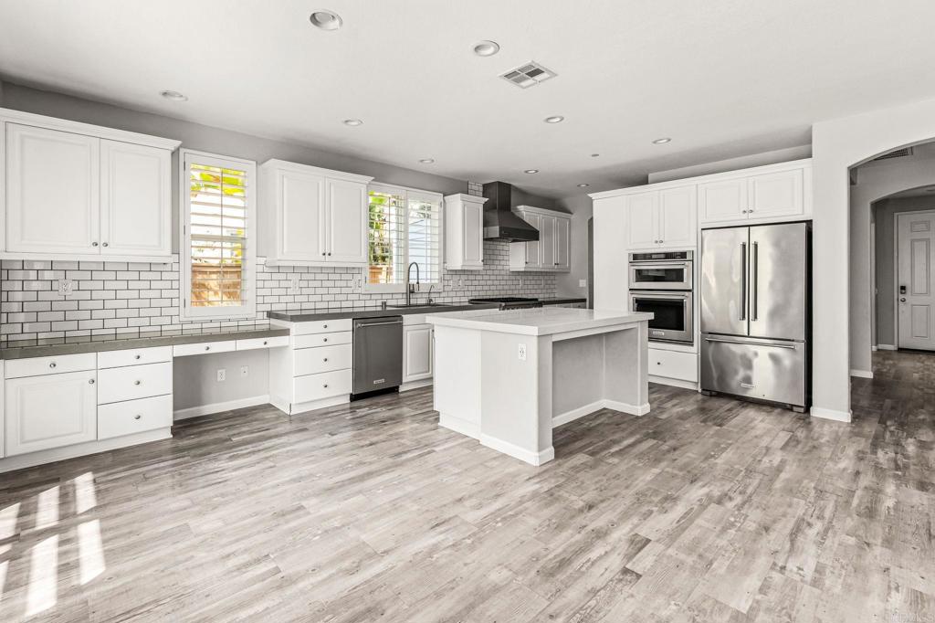 3848 Lake Park Street Fallbrook, CA 92028 - Photo 11 of 35 a kitchen with stainless steel appliances granite countertop a stove a sink dishwasher a refrigerator and white cabinets with wooden floor