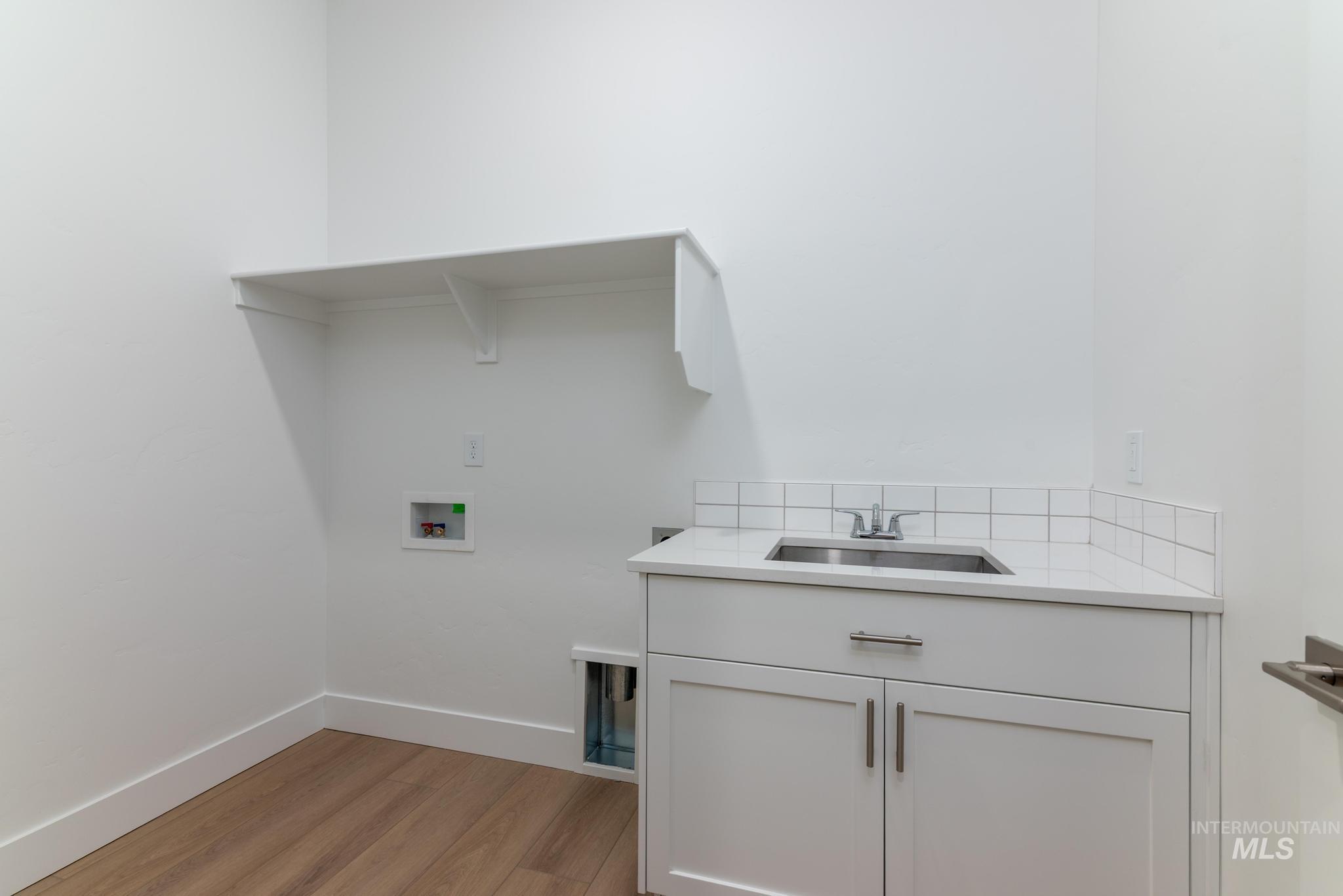5403 Juliet Rose Avenue Caldwell, ID 83607 - Photo 11 of 12 Laundry room featuring wood-finish flooring and a built-in shelf