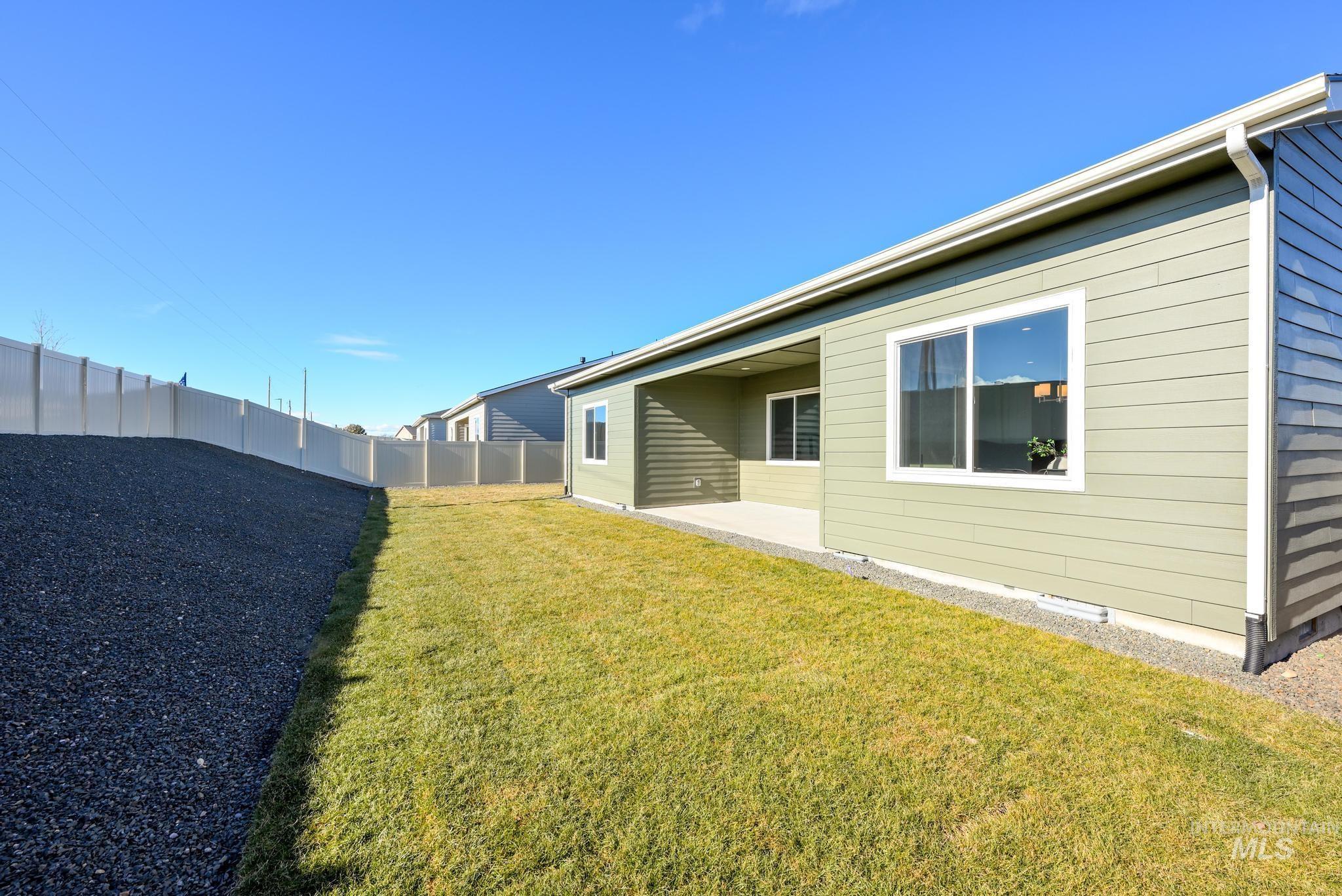 5403 Juliet Rose Avenue Caldwell, ID 83607 - Photo 12 of 12 Expansive backyard featuring a manicured lawn, a gravel-covered slope, and a full-height privacy fence