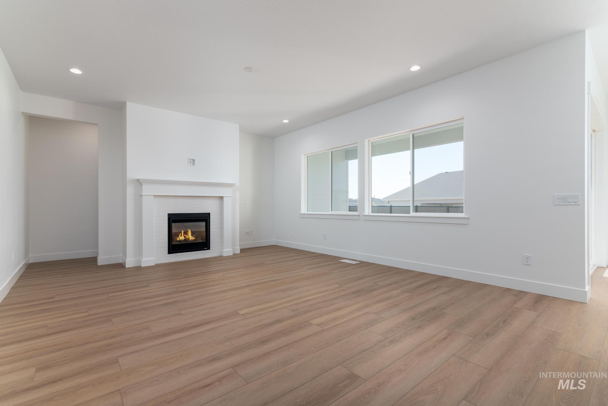 5403 Juliet Rose Avenue Caldwell, ID 83607 - Photo 2 of 12 Spacious interior featuring wood-finish flooring, a contemporary fireplace with a classic mantle, large windows for natural illumination, recessed lighting, and a neutral color palette