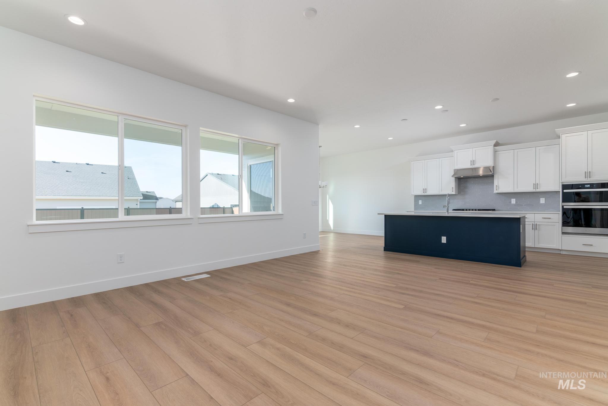 5403 Juliet Rose Avenue Caldwell, ID 83607 - Photo 3 of 12 Expansive open-concept living space featuring wood-finish flooring, recessed lighting, and a white interior palette