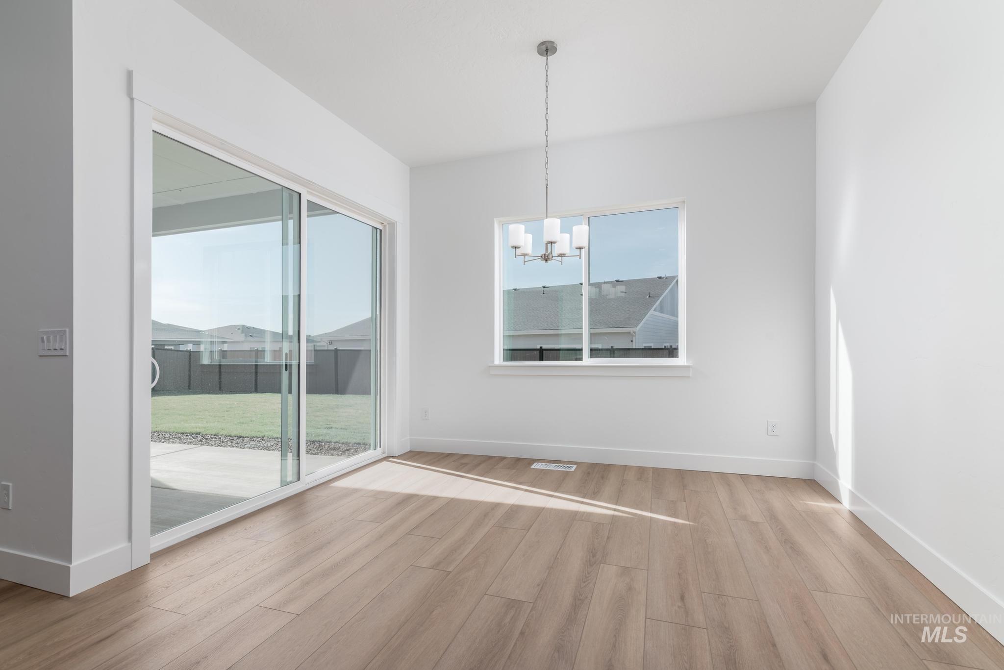 5403 Juliet Rose Avenue Caldwell, ID 83607 - Photo 6 of 12 Open-concept room featuring wood-finish flooring, a contemporary chandelier, and white baseboards