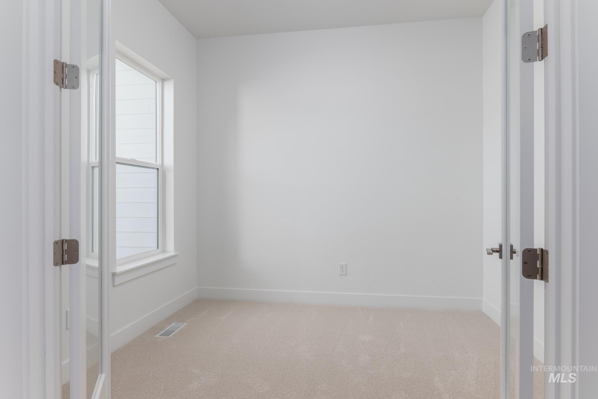 5403 Juliet Rose Avenue Caldwell, ID 83607 - Photo 7 of 12 Bright interior space featuring a window with white trim, light-colored carpeting, white baseboards, and a white wall finish