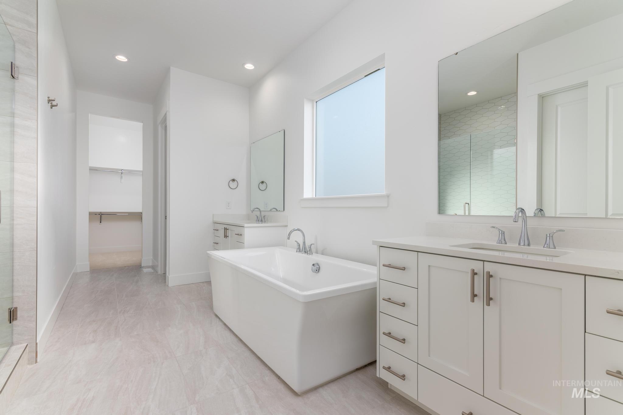 5403 Juliet Rose Avenue Caldwell, ID 83607 - Photo 9 of 12 Contemporary bathroom featuring a freestanding tub, dual vanities with white cabinetry and stone countertops, a glass-enclosed shower, and recessed lighting
