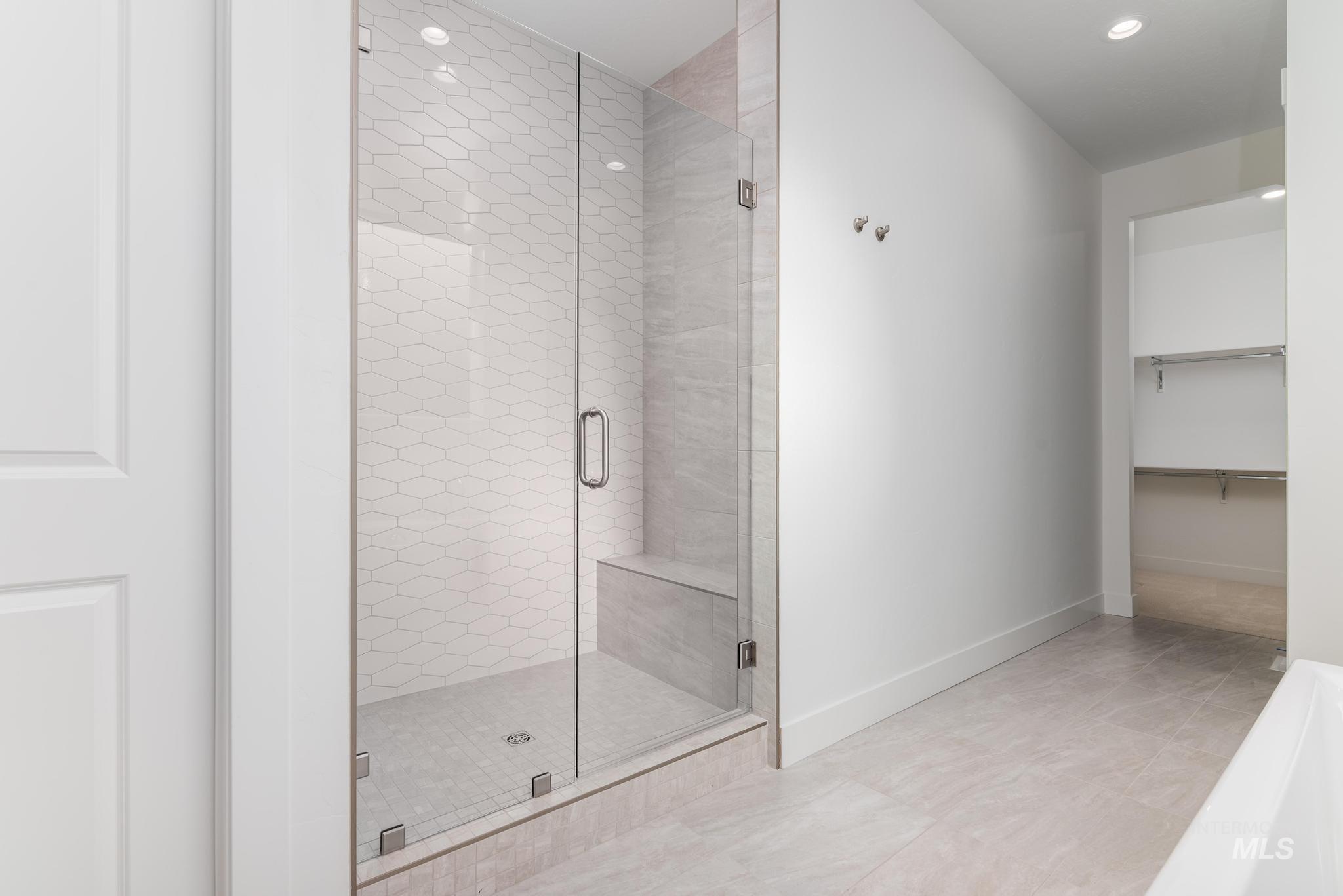 5403 Juliet Rose Avenue Caldwell, ID 83607 - Photo 10 of 12 Glass-enclosed shower with a built-in bench, hexagon-patterned wall tile, and a tile shower pan