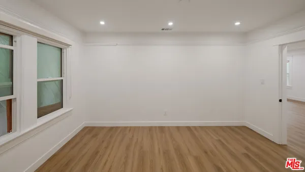 a view of an empty room with wooden floor and a window