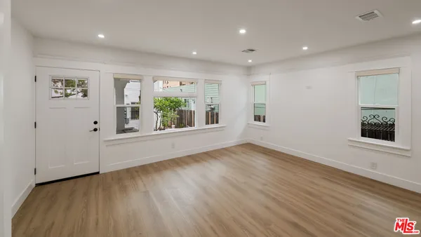 an empty room with wooden floor and windows