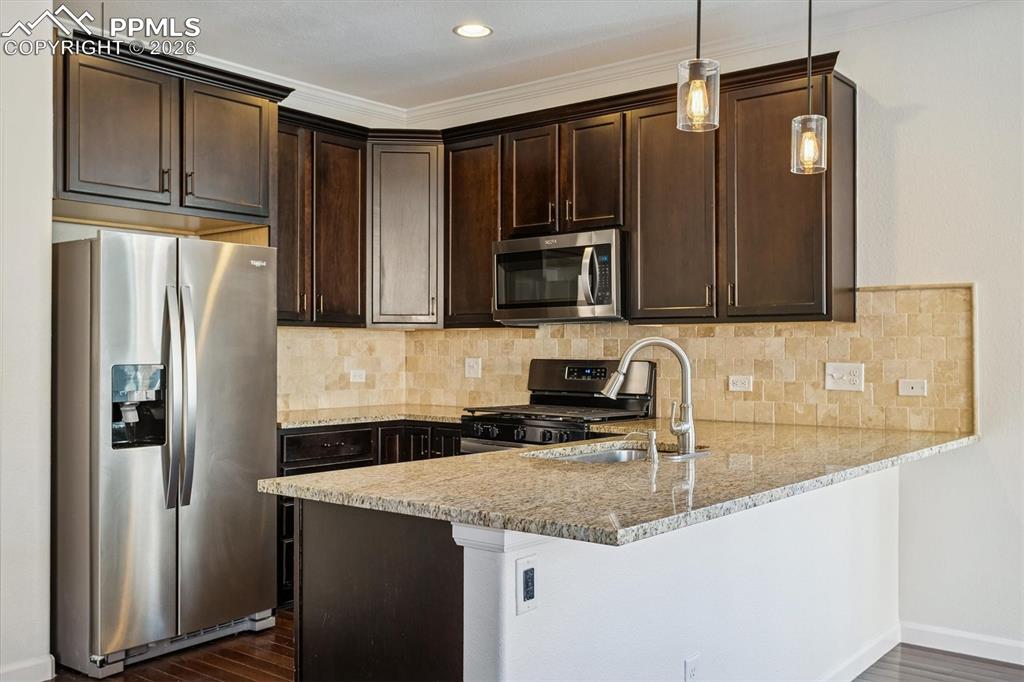 960 Fire Rock Place Colorado Springs, CO 80921 - Photo 7 of 30 a kitchen with stainless steel appliances granite countertop a refrigerator a stove and a sink with wooden cabinets