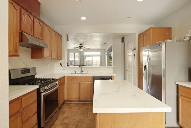 a kitchen with stainless steel appliances granite countertop a stove a sink and a refrigerator