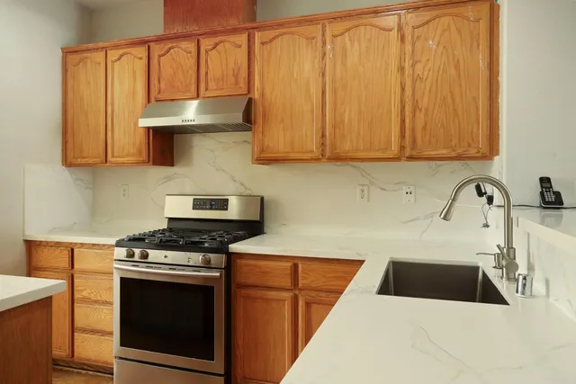 a kitchen with granite countertop a sink a stove and cabinets