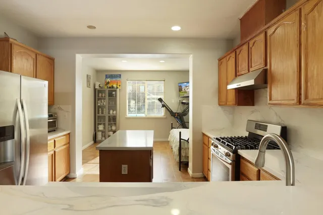 a kitchen with stainless steel appliances granite countertop a refrigerator a stove and a sink with wooden floors