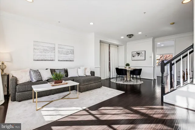 a kitchen with stainless steel appliances granite countertop a refrigerator a stove top oven a sink a dining table and chairs with wooden floor