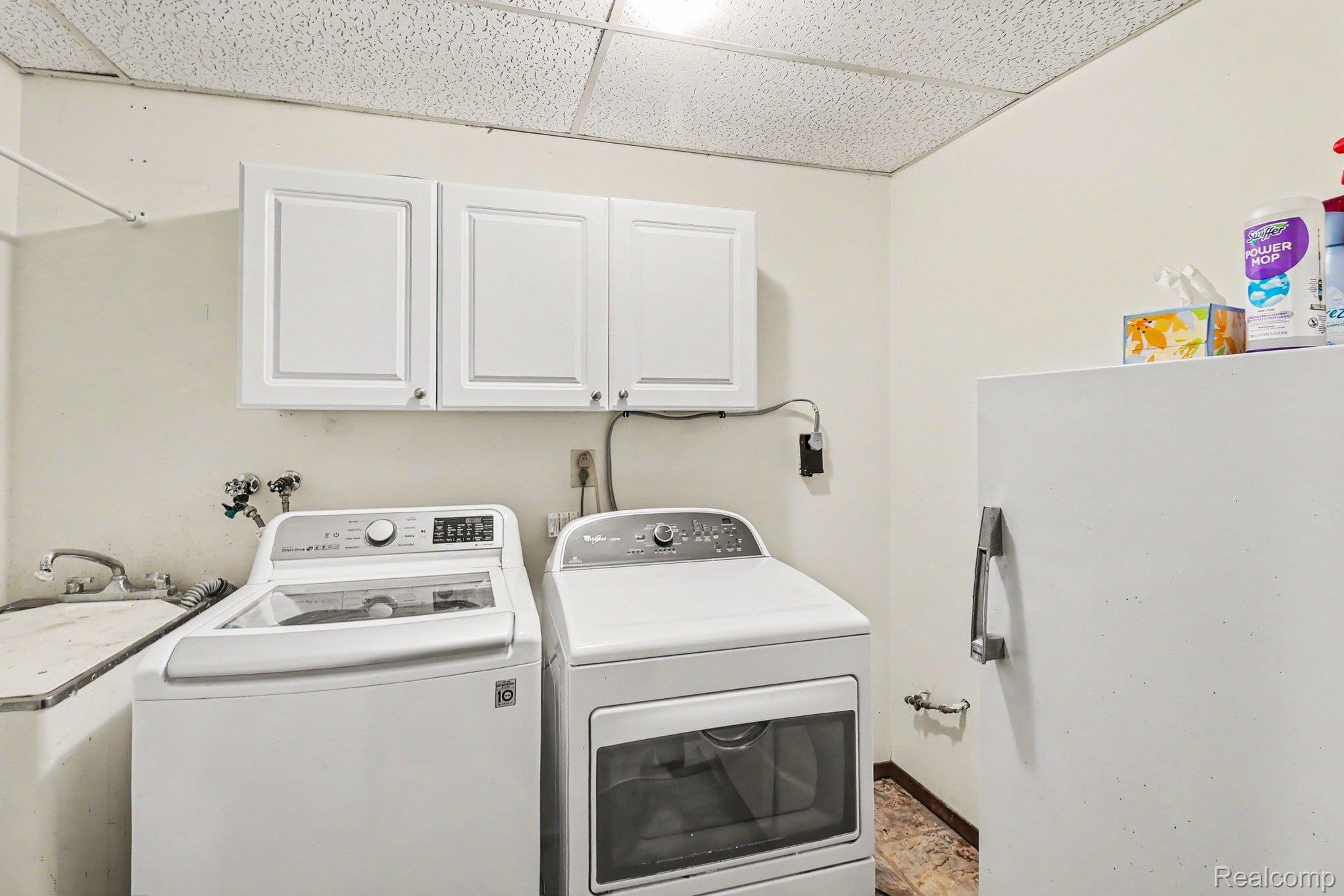 6300 North Raddatz Road Fowlerville, MI 48836 - Photo 34 of 42 Utility room featuring upper cabinetry, a sink basin, and a drop ceiling