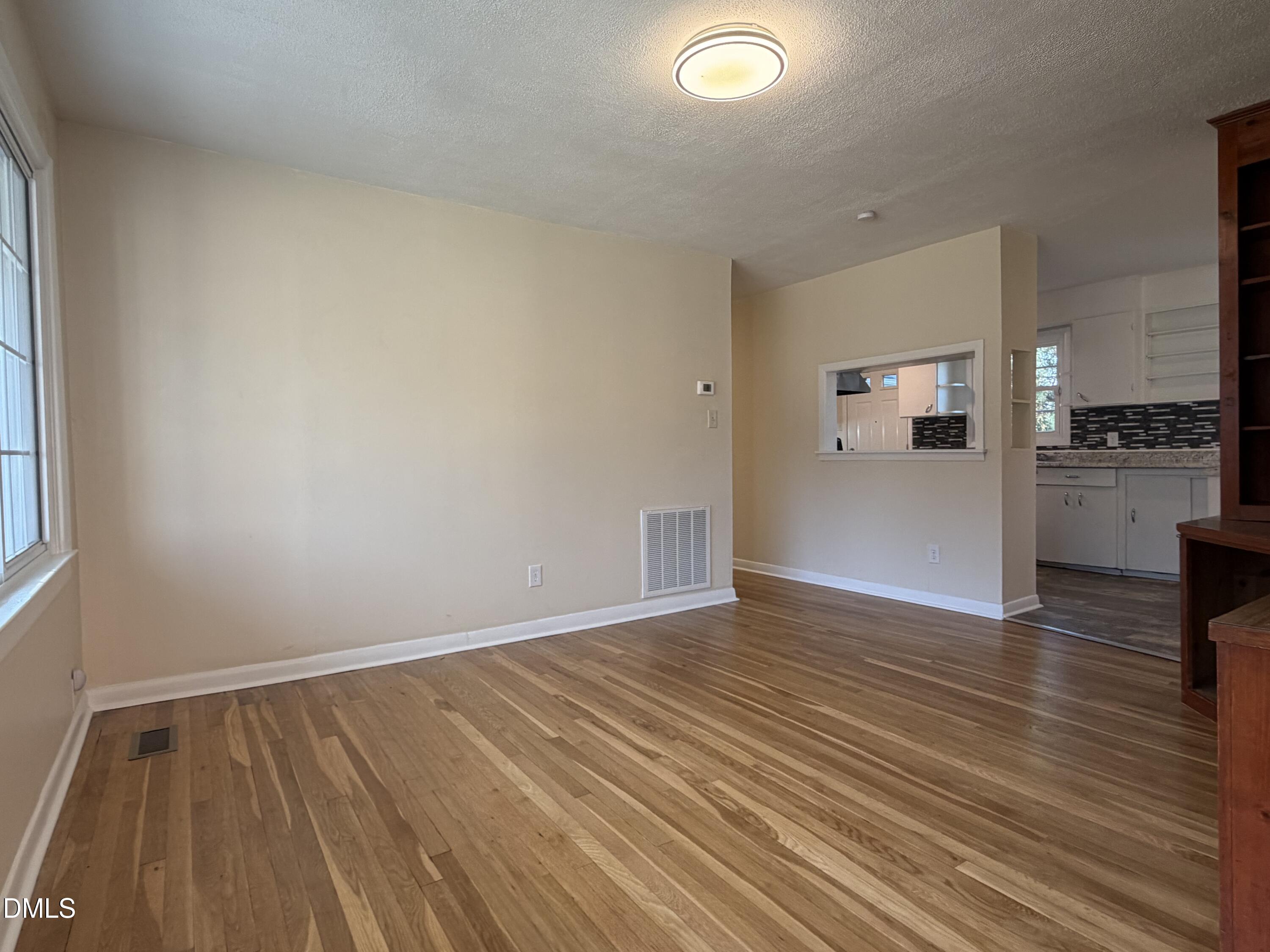 503 Spring Avenue Spring Lake, NC 28390 - Photo 7 of 36 an empty room with wooden floor and a kitchen