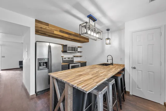 a kitchen with granite countertop a refrigerator and wooden floor