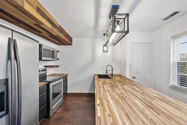 a kitchen with stainless steel appliances granite countertop a sink a stove and refrigerator