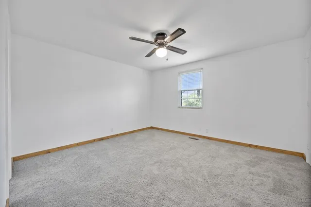 an empty room with window and ceiling fan