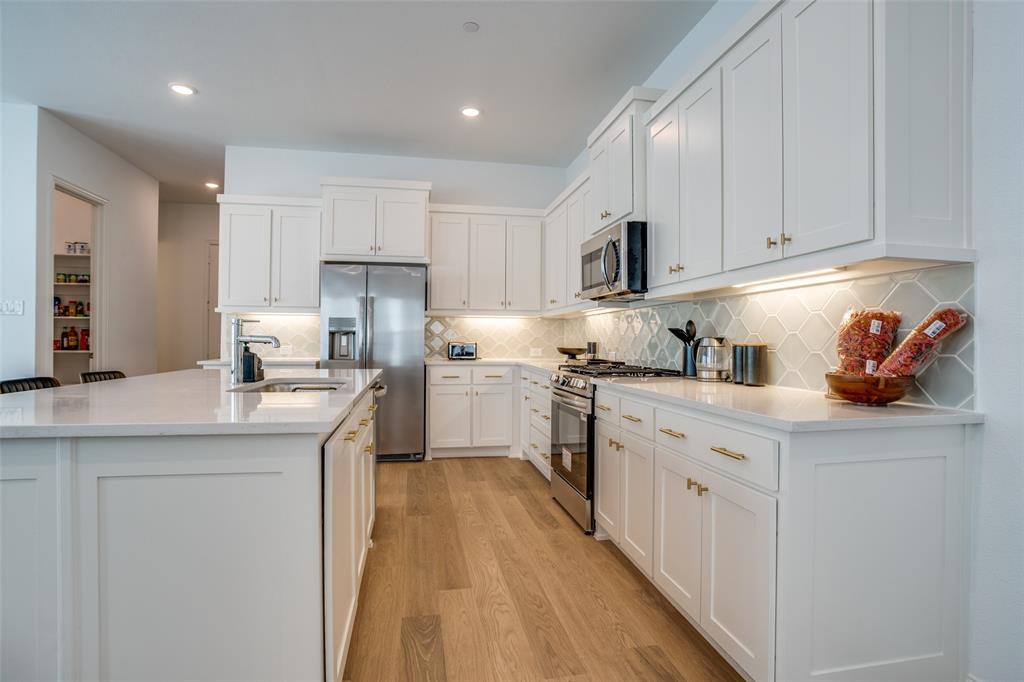 15603 Palmwood Road Frisco, TX 75033 - Photo 5 of 12 a kitchen with kitchen island granite countertop a sink a counter top space stainless steel appliances and cabinets