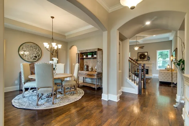 a dining room with wooden floor a chandelier a wooden table and chairs