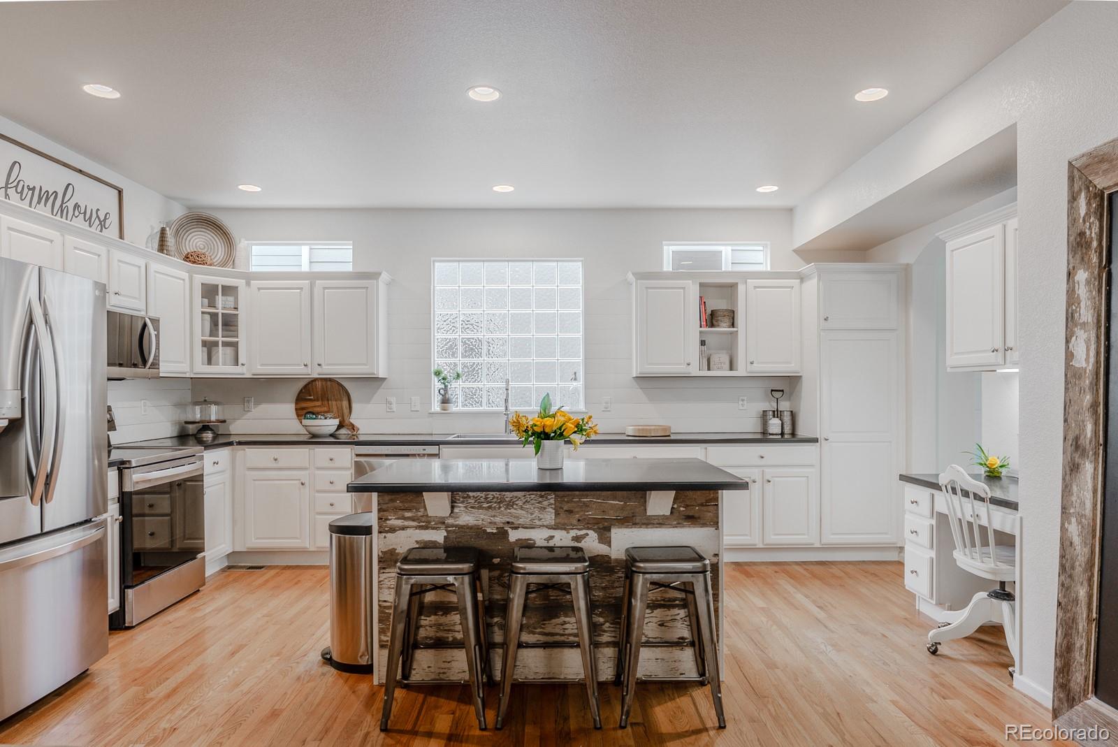 8367 Devinney Street Arvada, CO 80005 - Photo 3 of 41 a kitchen with a table a sink cabinets and stainless steel appliances