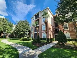 a view of a big yard in front of a brick house with plants and large trees