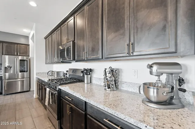 a kitchen with granite countertop a sink a stove and refrigerator