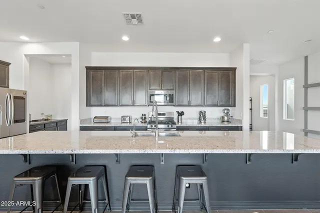 a kitchen with granite countertop a table chairs sink and wooden cabinets