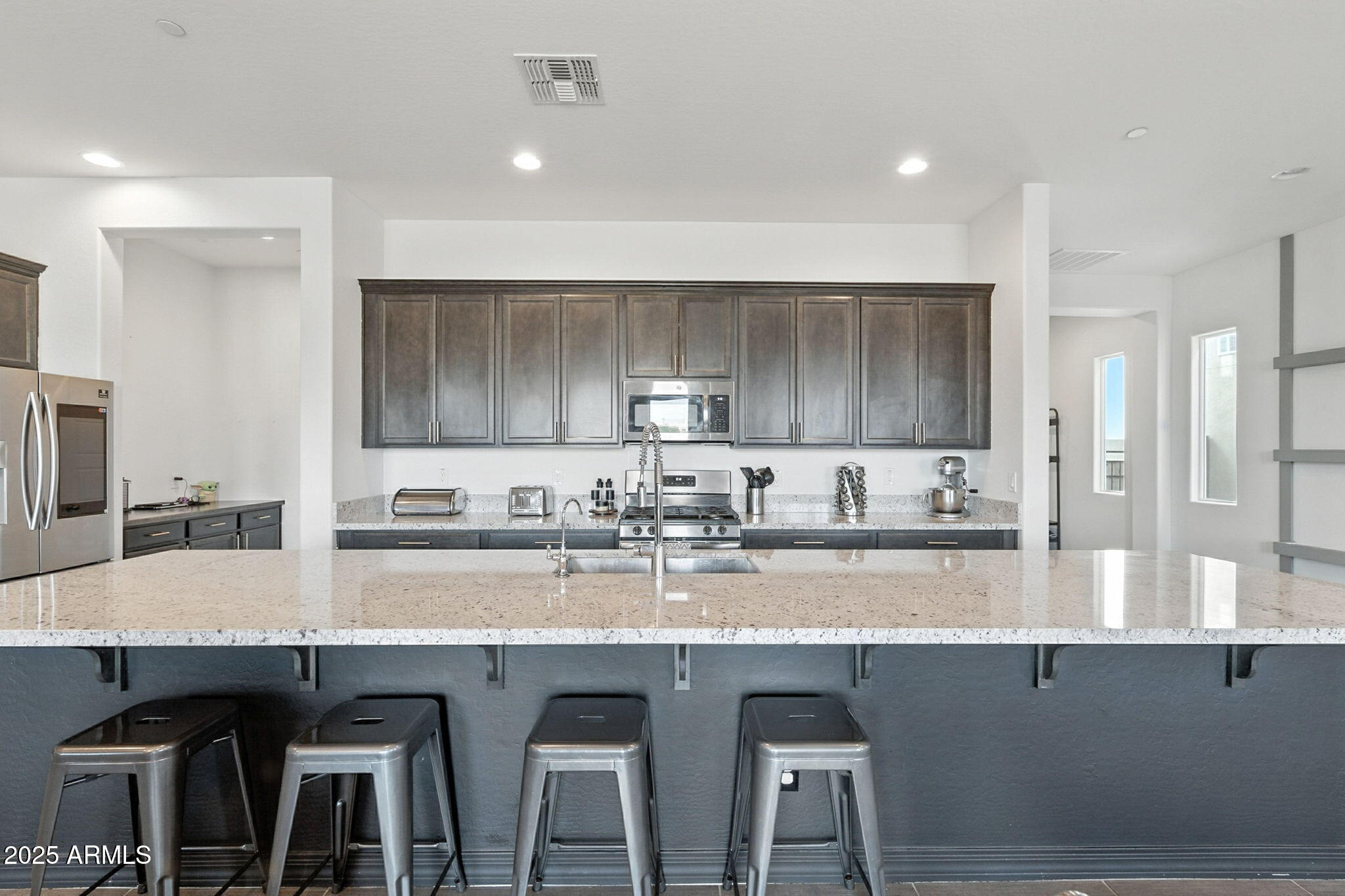 7236 West Phelps Road Peoria, AZ 85382 - Photo 27 of 53 a kitchen with granite countertop a table chairs sink and wooden cabinets