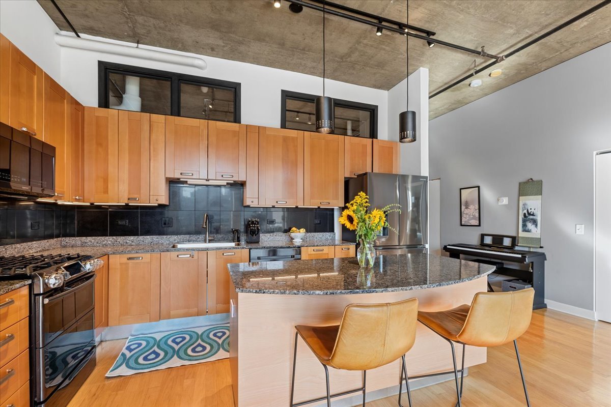 111 South Morgan Street, Unit 823 Chicago, IL 60607 - Photo 8 of 20 a kitchen with stainless steel appliances kitchen island granite countertop a stove and cabinets