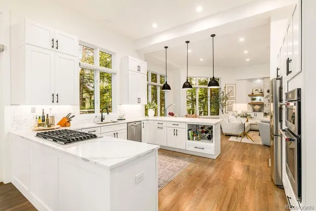 a kitchen with stainless steel appliances a stove a sink and white cabinets with wooden floor