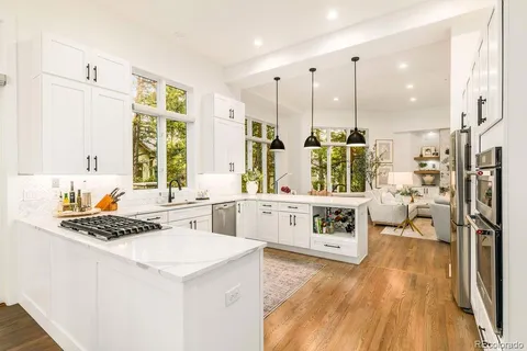 a kitchen with stainless steel appliances a stove a sink and white cabinets with wooden floor