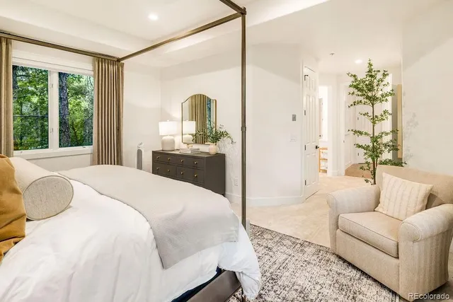 a spacious bedroom with a bed a couch and a large window