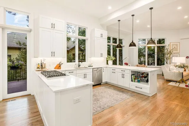 a kitchen with stainless steel appliances a stove a sink and white cabinets with wooden floor