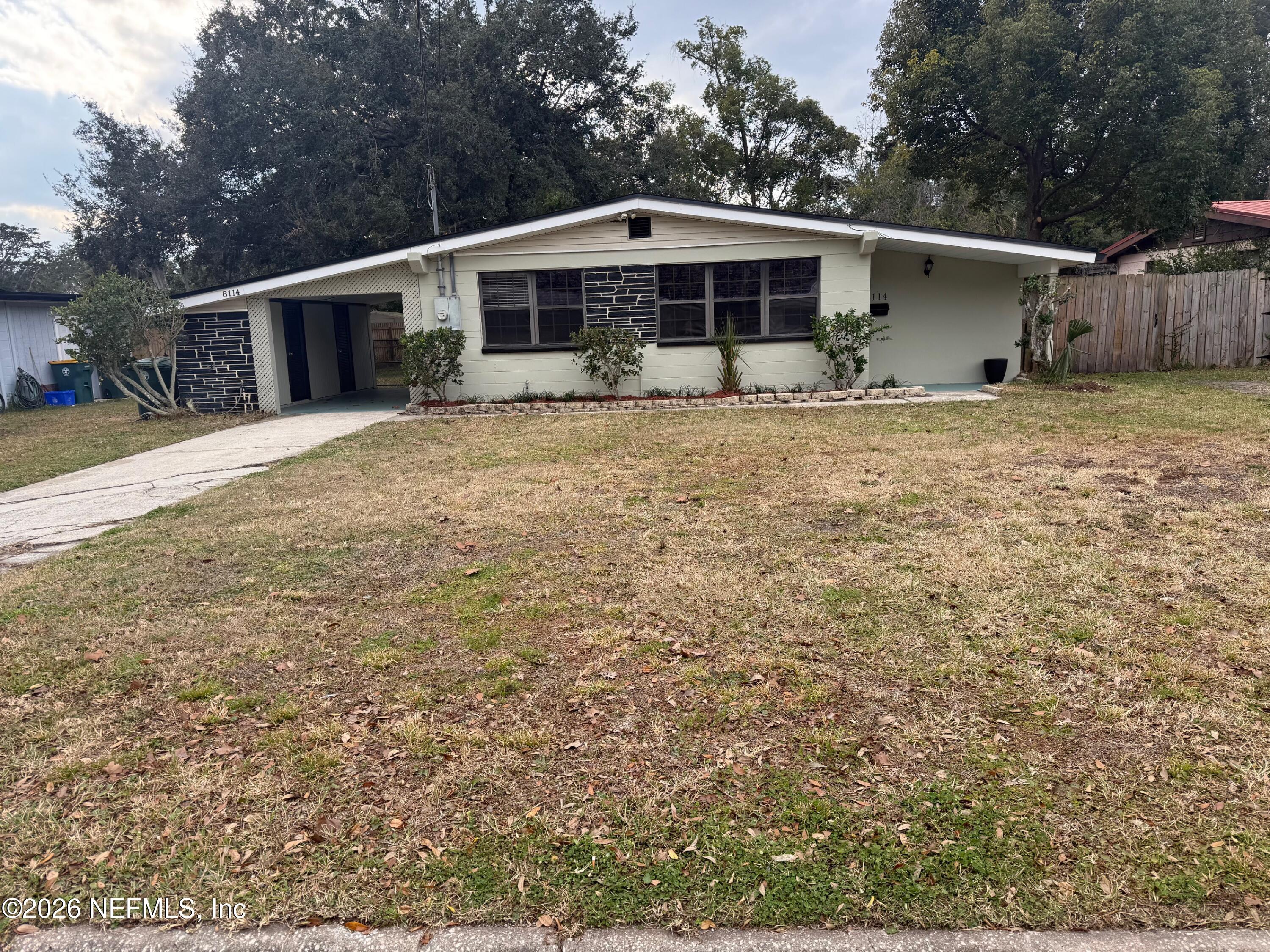 a front view of house with yard and trees in the background