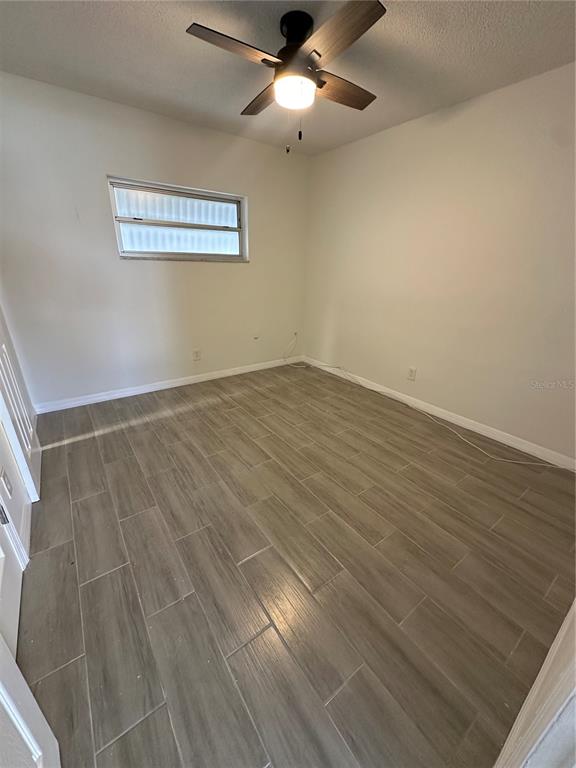 250 Rosery Road Northwest, Unit 227 Largo, FL 33770 - Photo 11 of 18 an empty room with wooden floor chandelier fan and windows