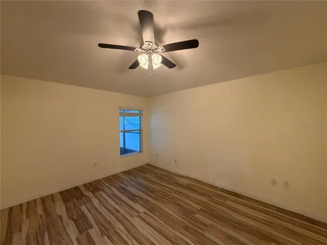 a view of empty room with window and ceiling fan