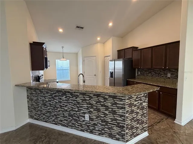 a kitchen with stainless steel appliances kitchen island granite countertop a refrigerator and a stove top oven