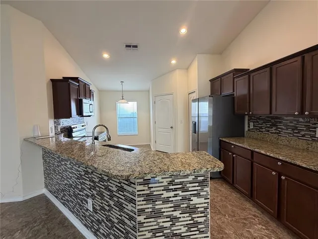 a kitchen with kitchen island granite countertop a sink and refrigerator