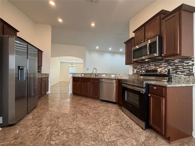 a kitchen with stainless steel appliances granite countertop a stove a sink and a refrigerator