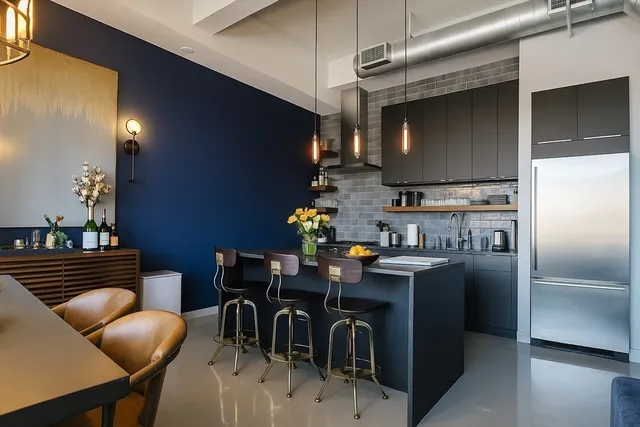 a kitchen with stainless steel appliances kitchen island granite countertop a table chairs in it and a wooden floors