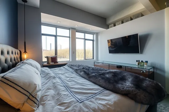 a living room with a bed a flat screen tv and a large window