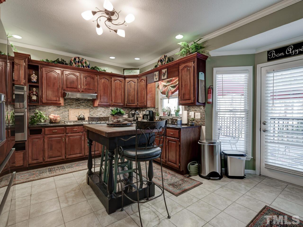 5933 Dunbarton Way Raleigh, NC 27613 - Photo 3 of 48 a kitchen with kitchen island granite countertop wooden cabinets a refrigerator a sink and a stove