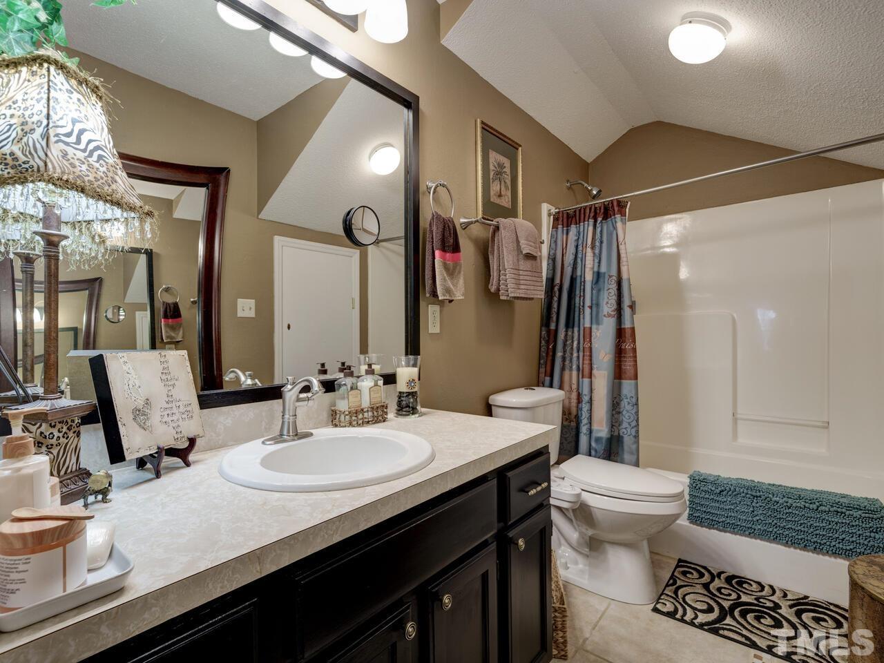 5933 Dunbarton Way Raleigh, NC 27613 - Photo 36 of 48 a bathroom with a granite countertop sink a toilet a mirror and shower