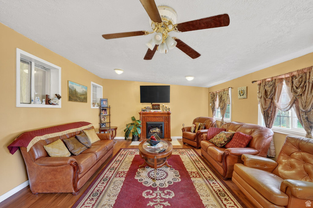 977 23rd Street Ogden, UT 84401 - Photo 19 of 29 Living room with wood finished floors, a fireplace, a textured ceiling, and a ceiling fan