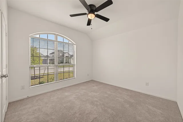 an empty room with windows and fan
