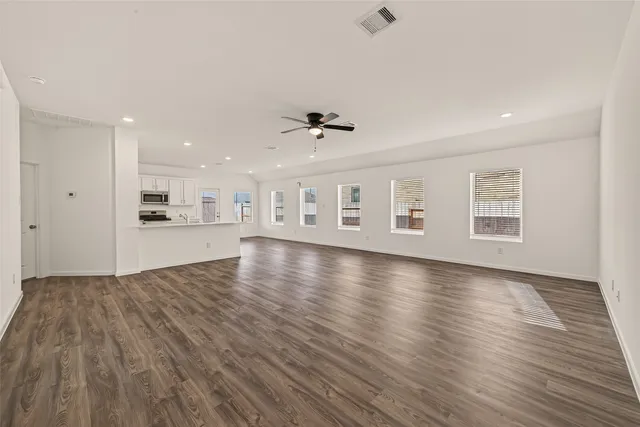 a view of an empty room with a window and wooden floor