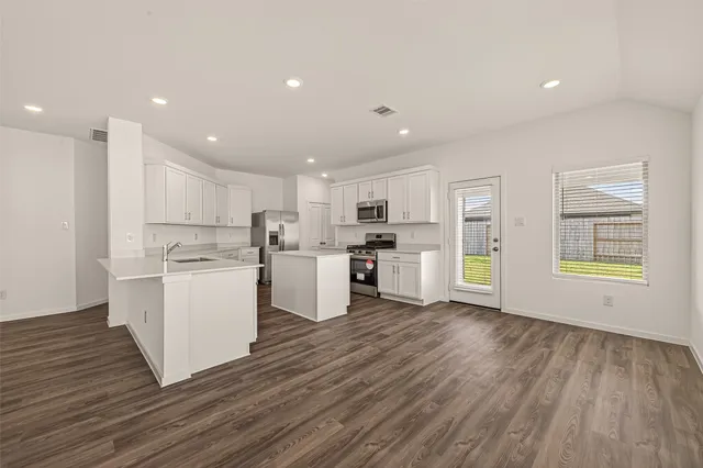 a kitchen with wooden floors and white cabinets