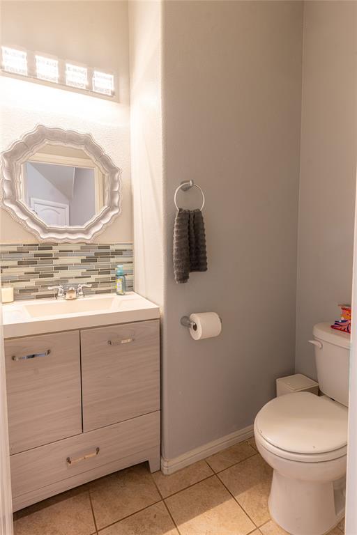 753 Rutherford Drive Crowley, TX 76036 - Photo 13 of 26 Bathroom featuring a single vanity with built-in storage, a decorative framed mirror, a tiled backsplash, and neutral tile flooring