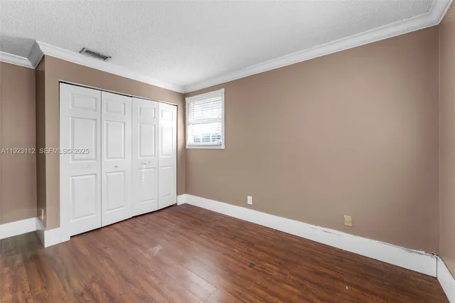 an empty room with wooden floor chandelier and windows