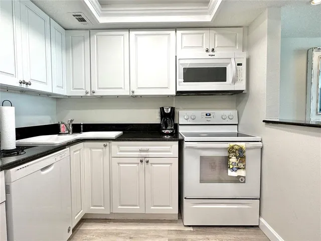 a kitchen with white cabinets and white appliances